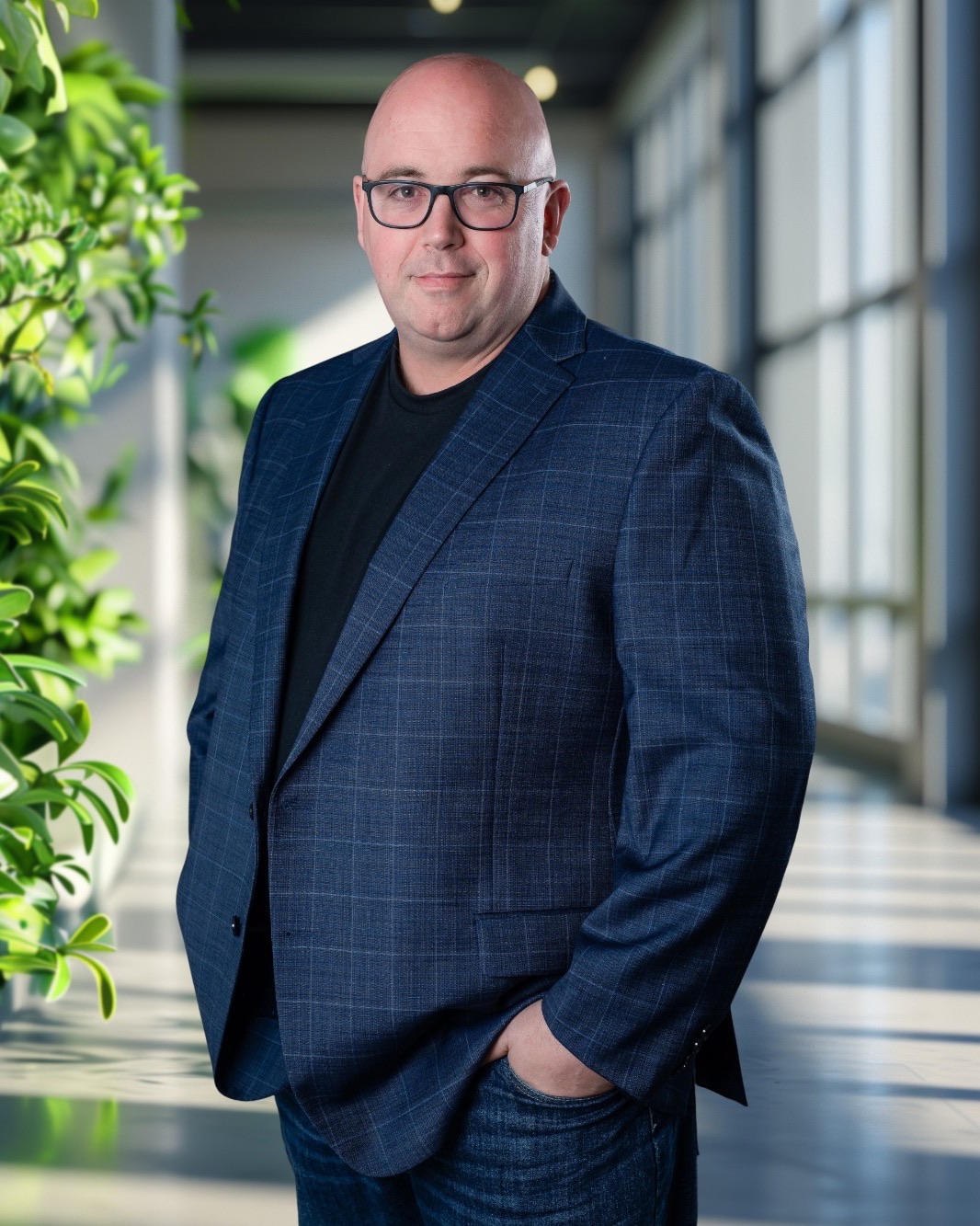Shaun Whynacht in a navy blazer, standing in a bright office corridor